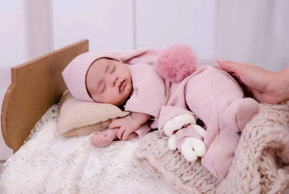 imagem de bebe menina com roupa rosa e cursinho branco dormindo