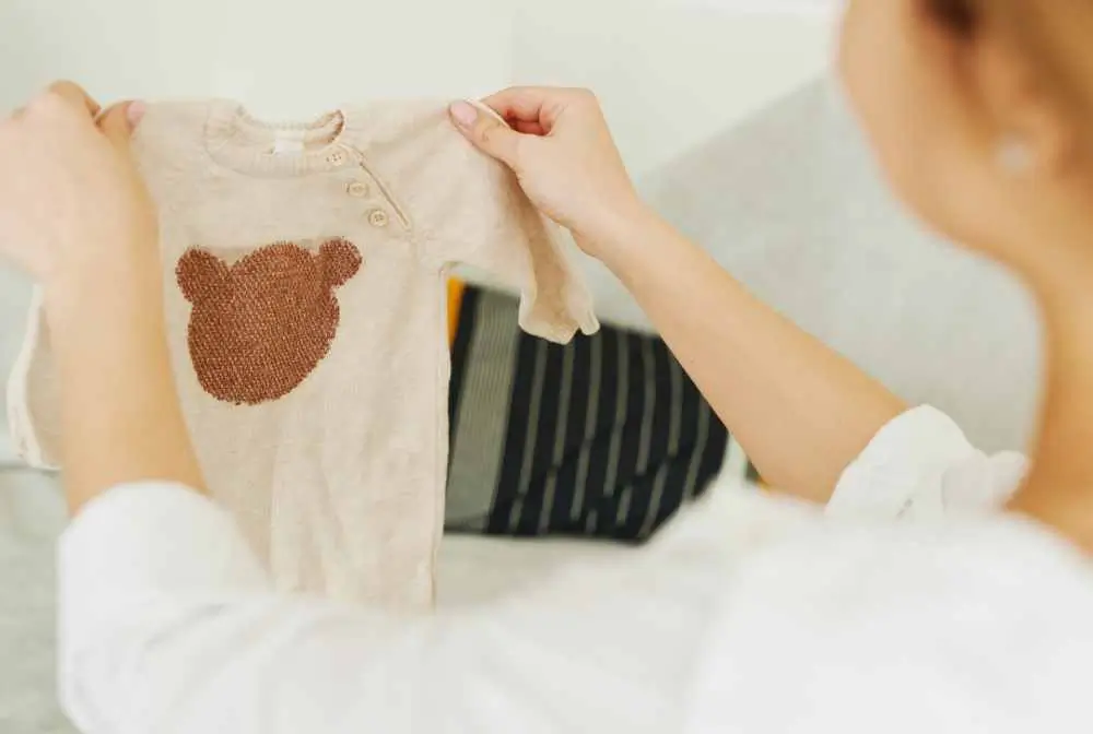 imagem demulher segurando um bode de bebe com aplique de cursinho a frente do corpo