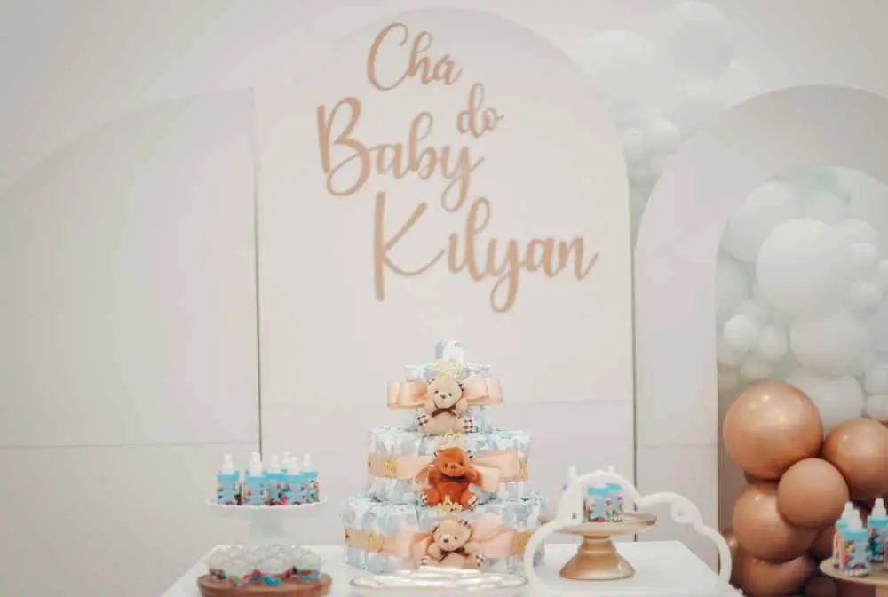 imagem de bolo e docinhos sobre a mesa e faixa com os dizeres de cha do bebe kilyan