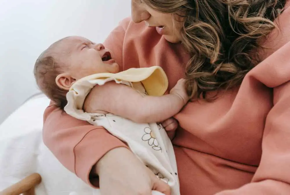 imagem de mulher segurando bebe chorando no colo
