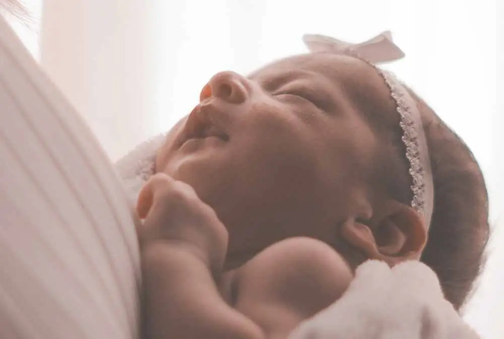 imagem de bebe menina com laço branco na cabeça dormindo