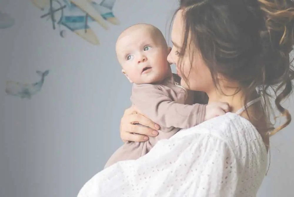 imagem de mulher de ladosegurando bebe no colo